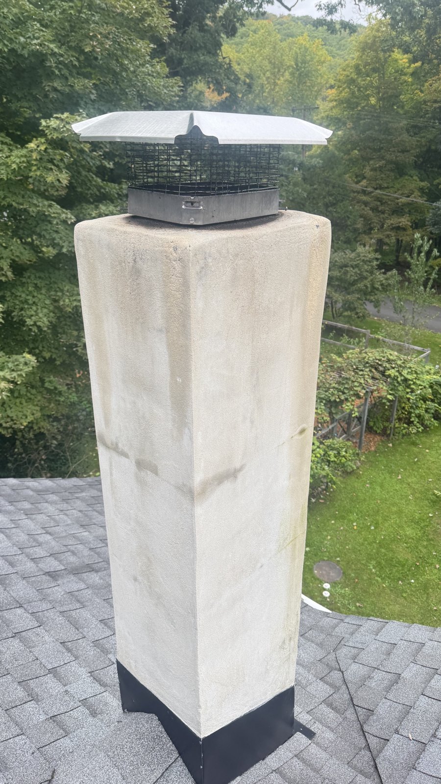 Stucco chimney in Rockaway, NJ with water staining, a horizontal crack and a basic steel cap
